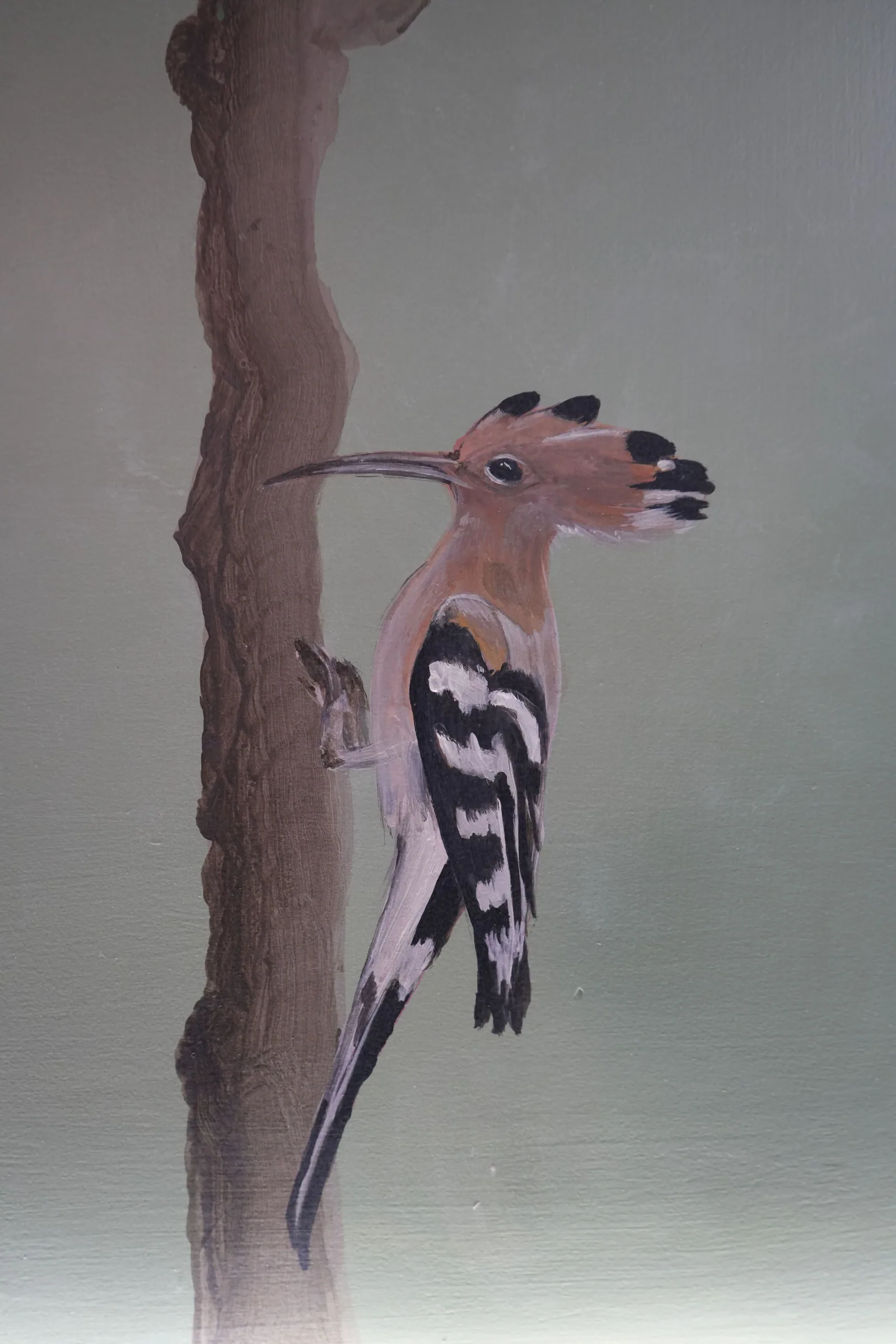 A painted hoopoe with its crest raised, climbing the trunk of a painted tree