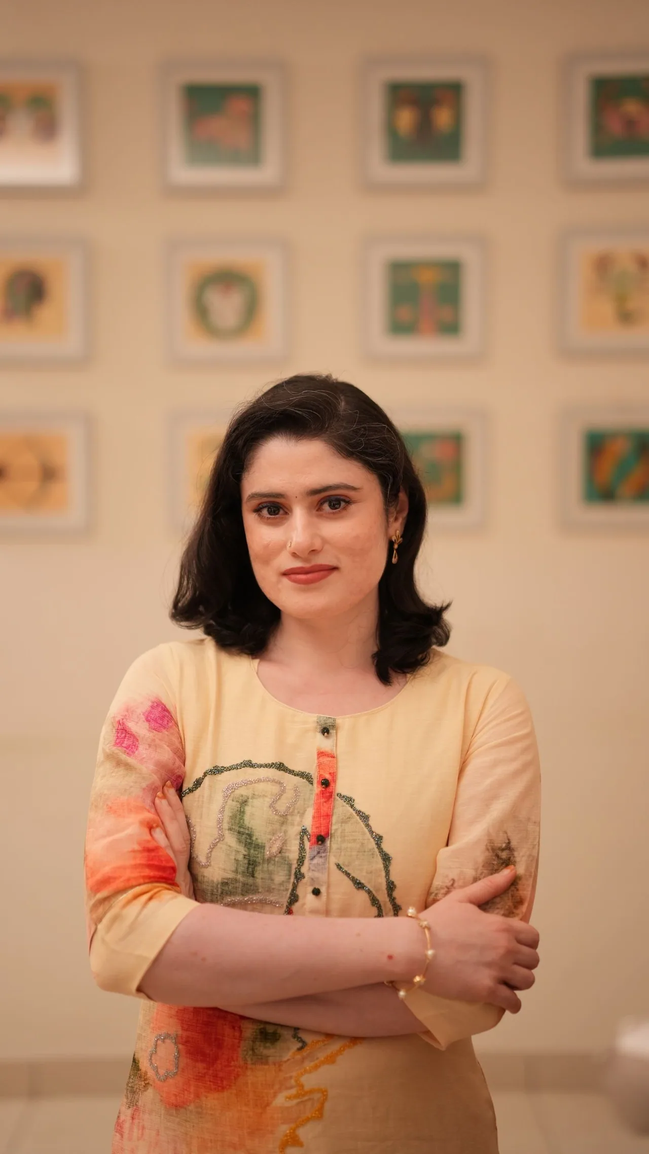 Yuvasri G standing in front of a wall of her framed paintings