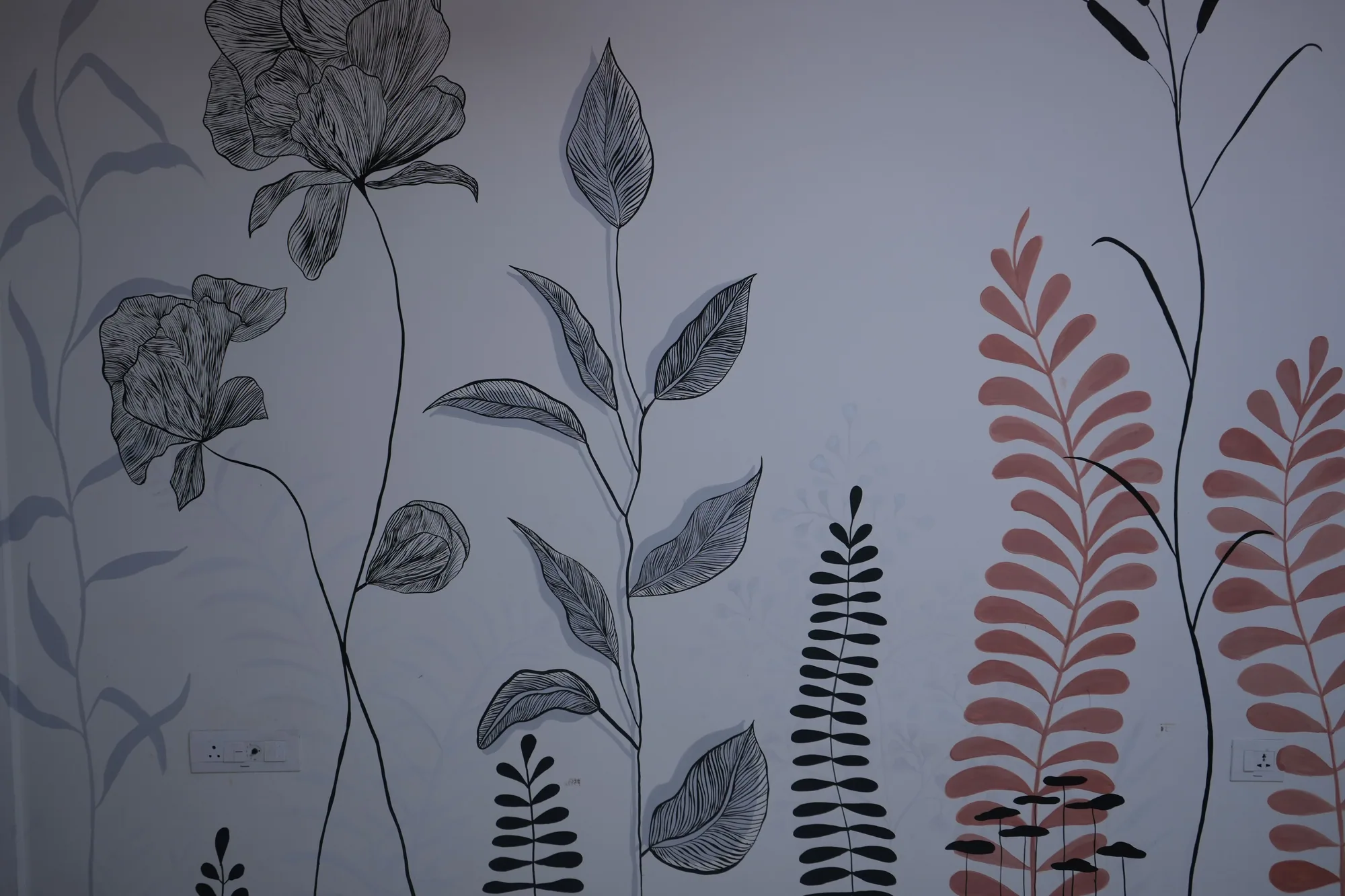 The botanical wall seen closer, showing the weight of the ink line against the flat coral fronds