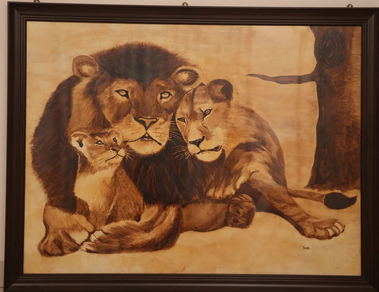 Large painting of a male lion with a lioness and two cubs resting against him, in warm ochres and browns, in a dark wooden frame